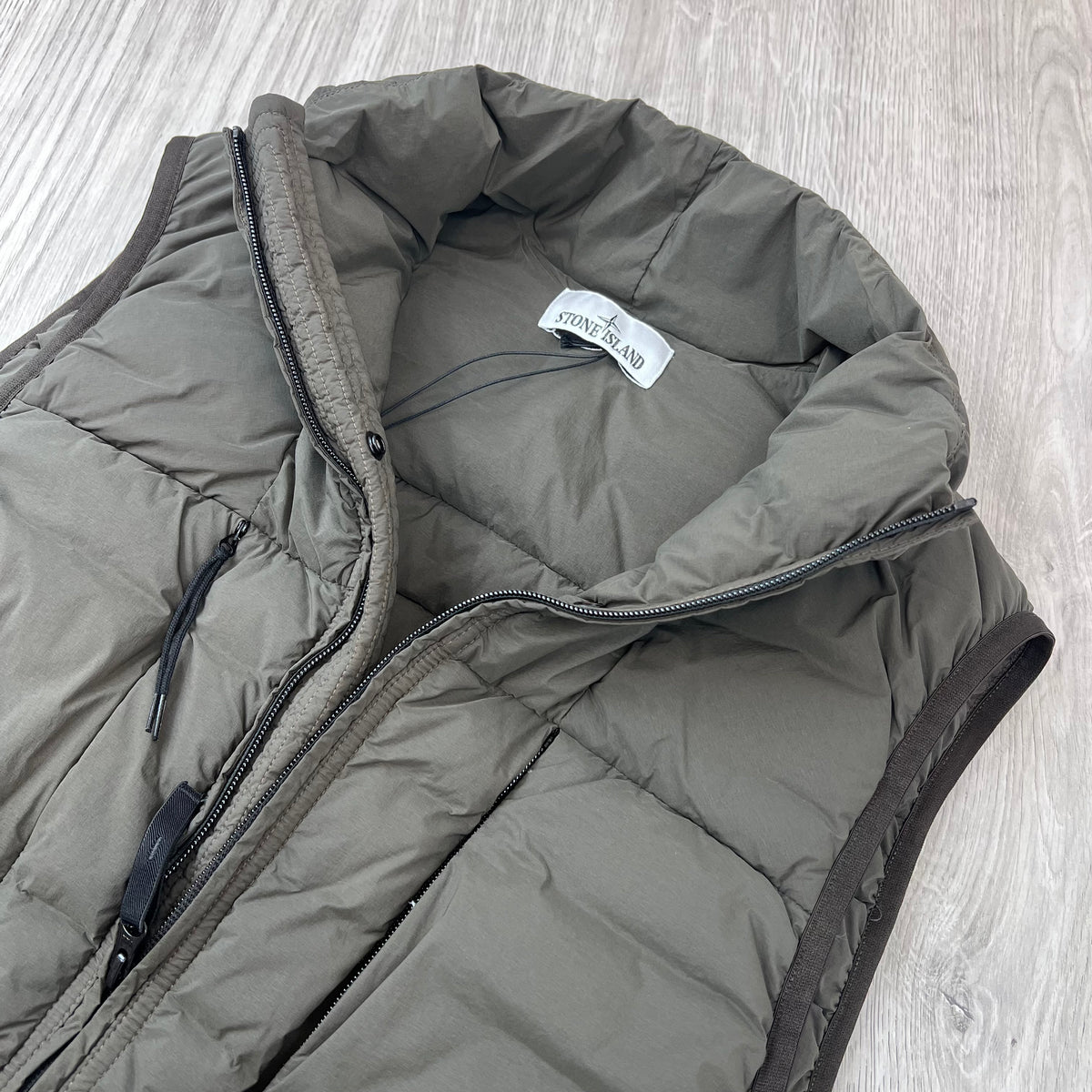 A close view of the open collar on a Stone Island Seamless Tunnel Nylon Down-TC Down Gilet in Coal Grey.
