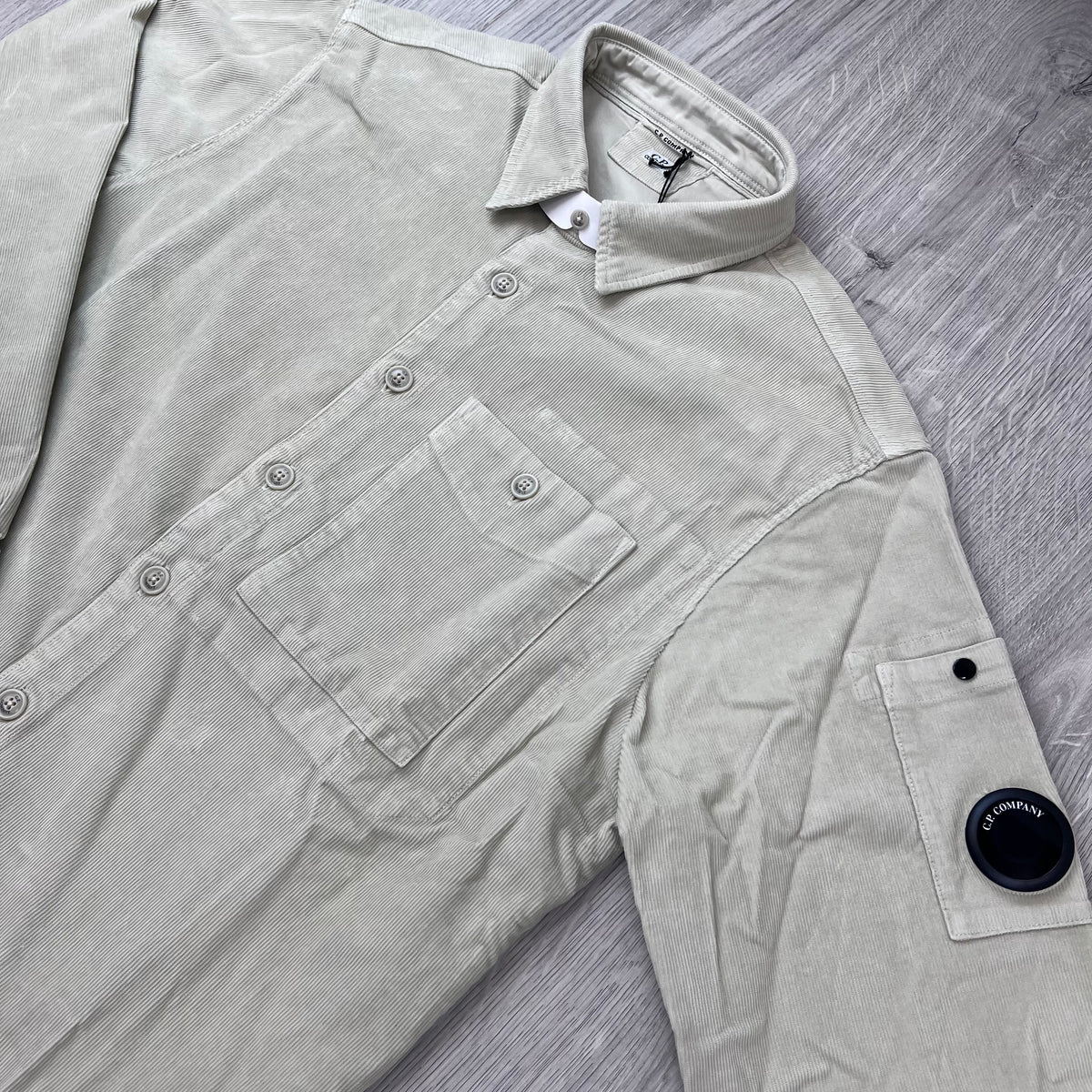 Angled view of the folded collar, button placket and sleeve lens on a CP Company Cotton Corduroy Overshirt in Silver Birch.