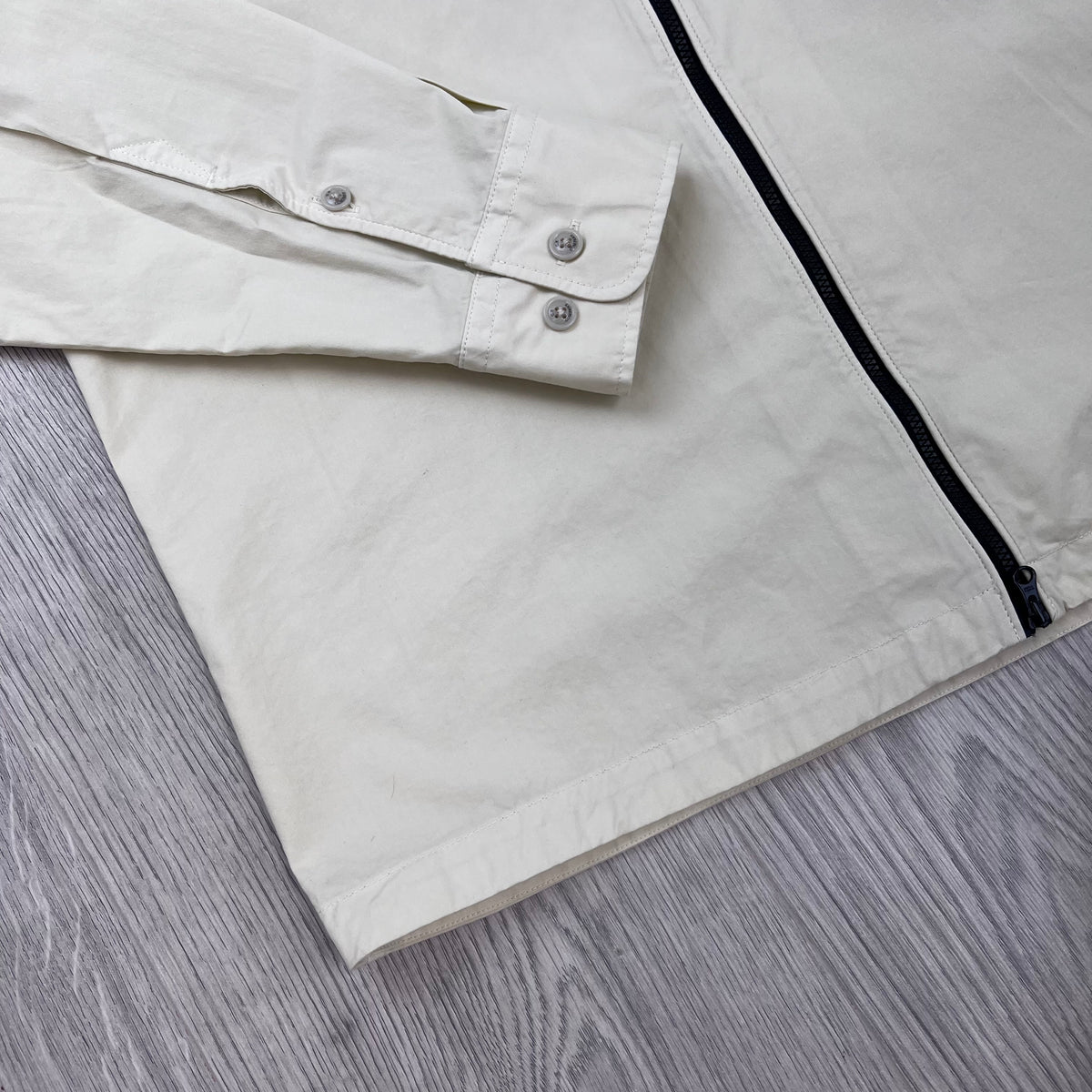 Angled view of the button-cuffs and straight hem on a CP Company Zip Overshirt in Silver Birch.