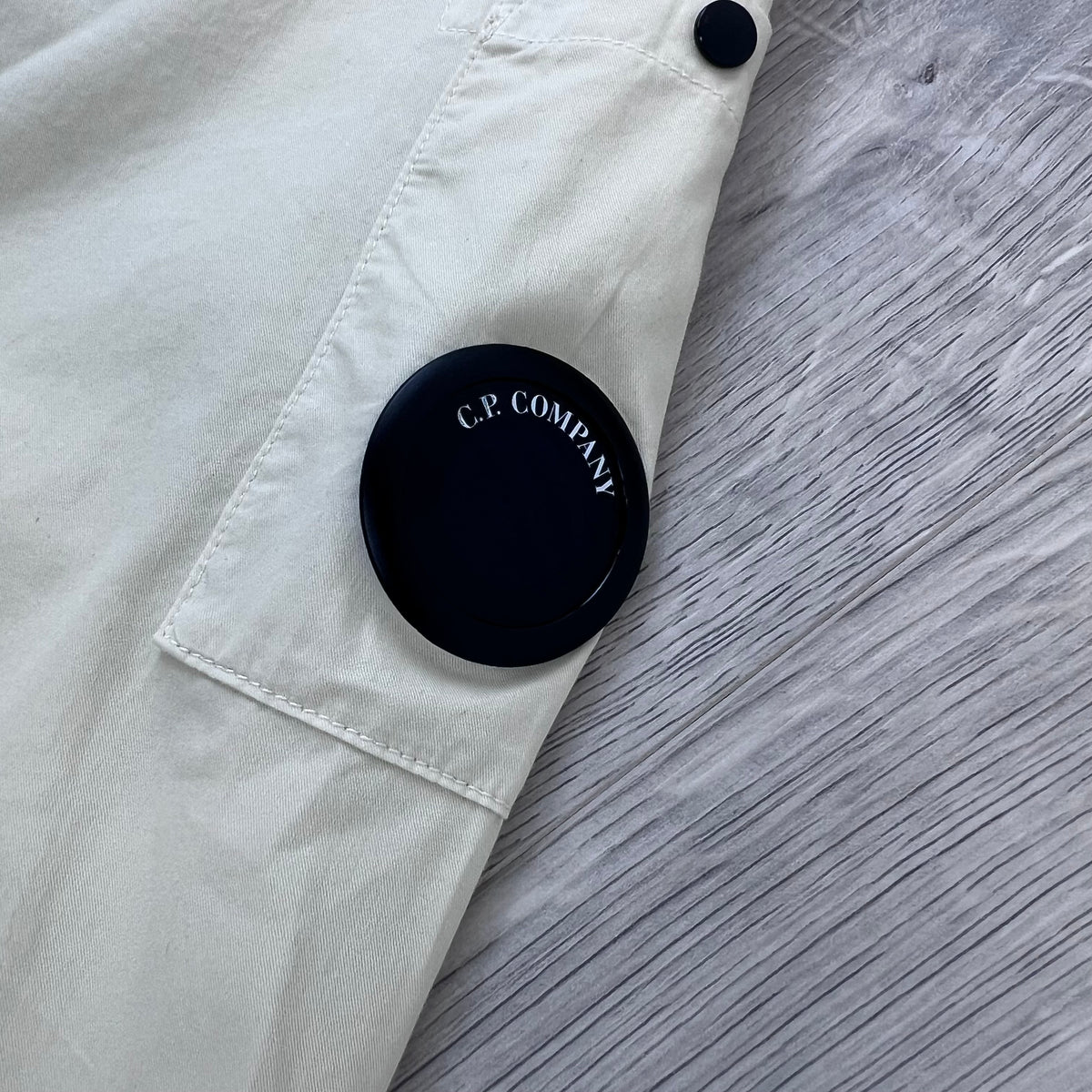 Close up view of the NFC sleeve lens detail on the CP Company Zip Overshirt in Silver Birch.