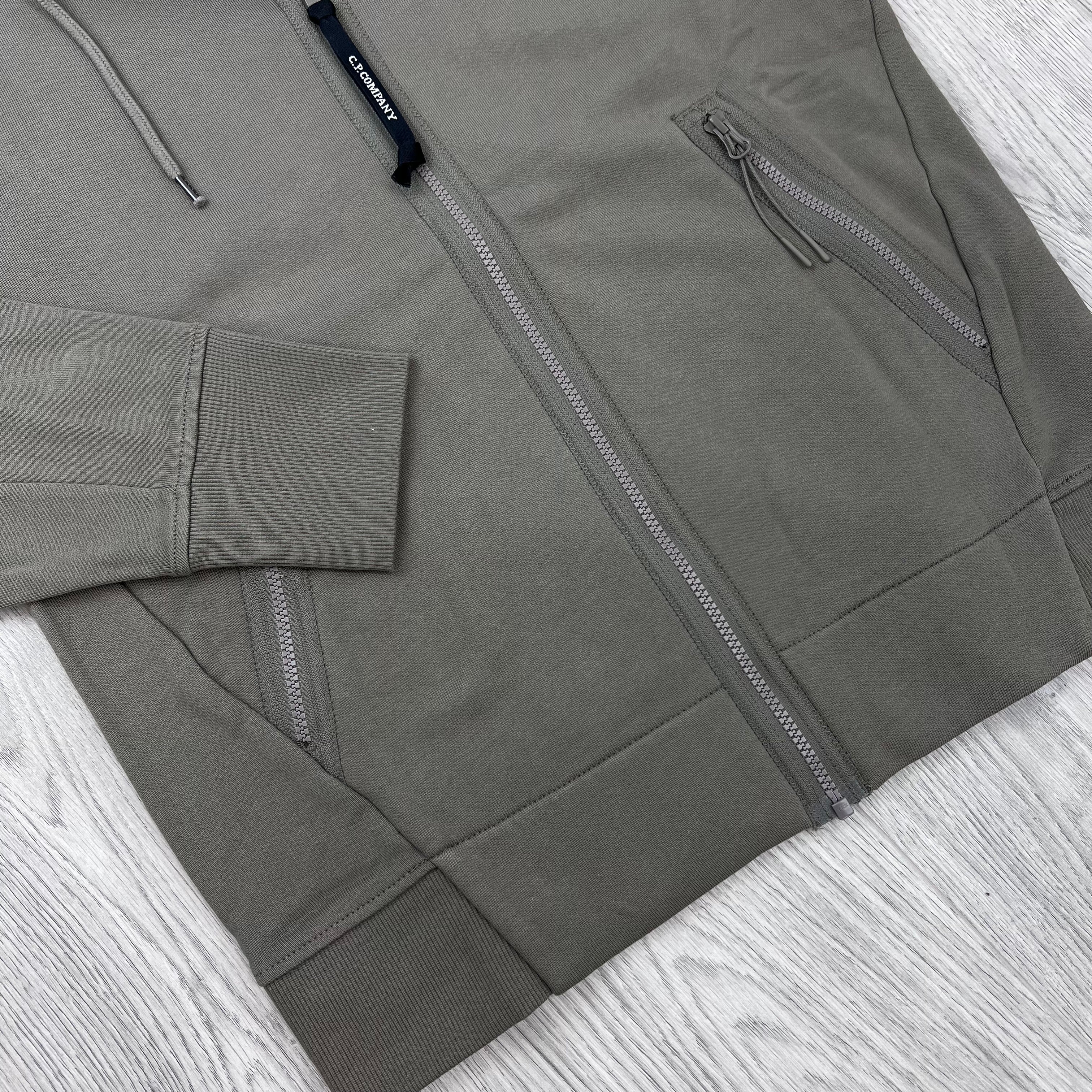 A close up view of the zip and hem on a CP Company Raised Fleece Zip Hoodie in Fallen Rock.