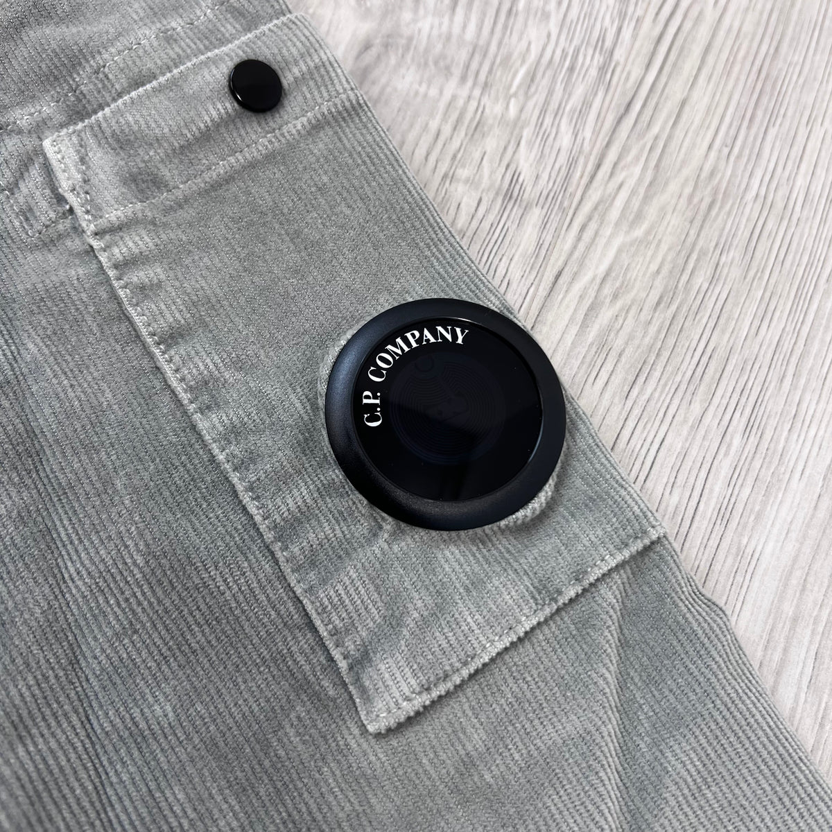 Close up view of the NFC sleeve lens detail on a CP Company Cotton Corduroy Overshirt in Flint Grey.
