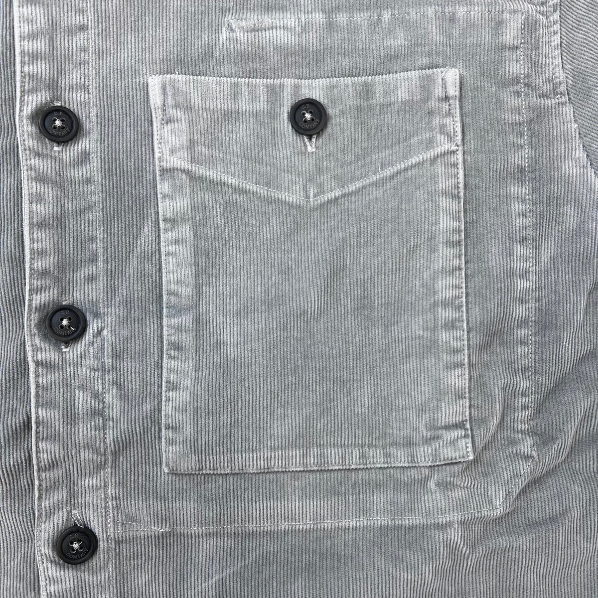 Close up view of the flap button pocket on a CP Company Cotton Corduroy Overshirt in Flint Grey.