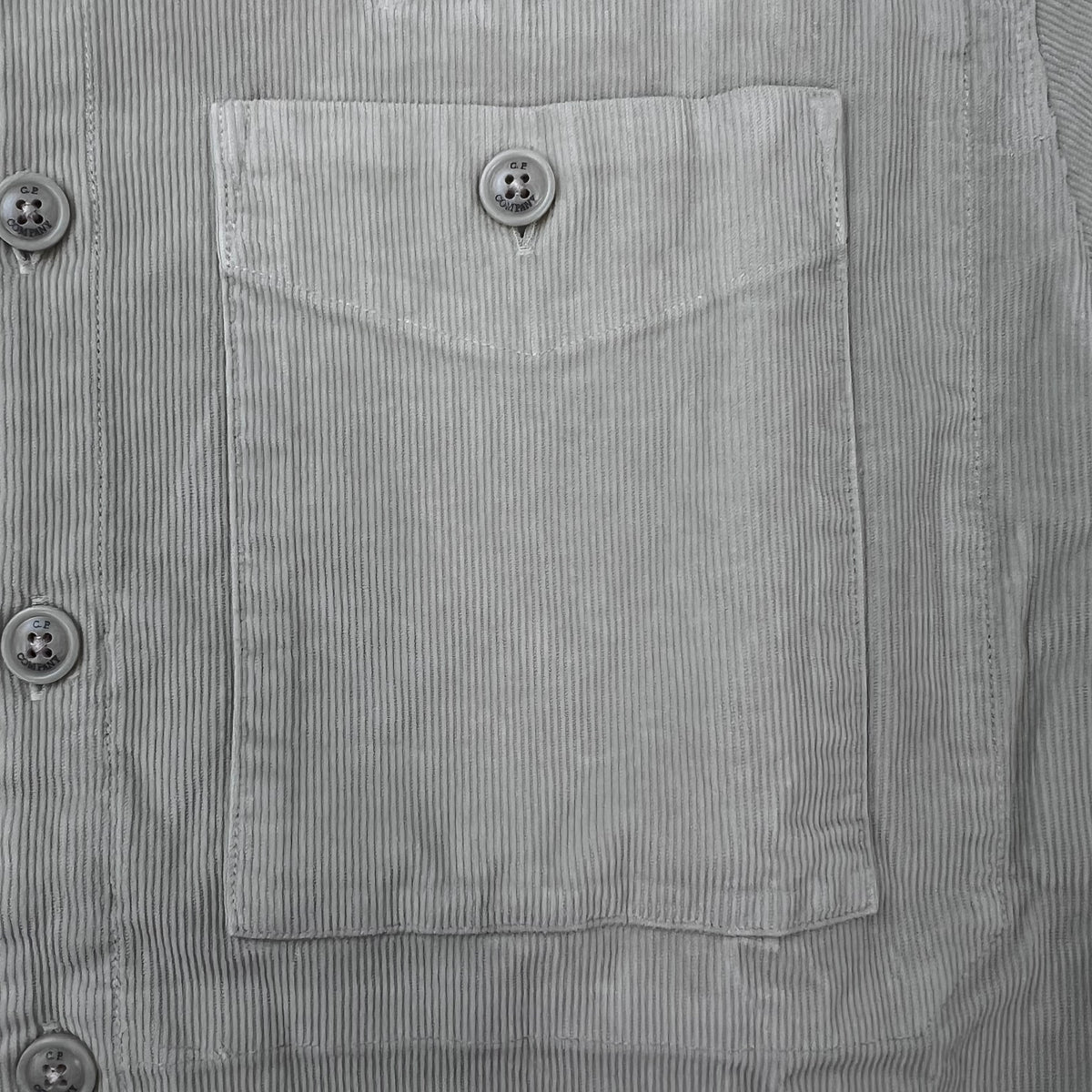 Close up view of the flap button pocket on a CP Company Cotton Corduroy Overshirt in Silver Birch.