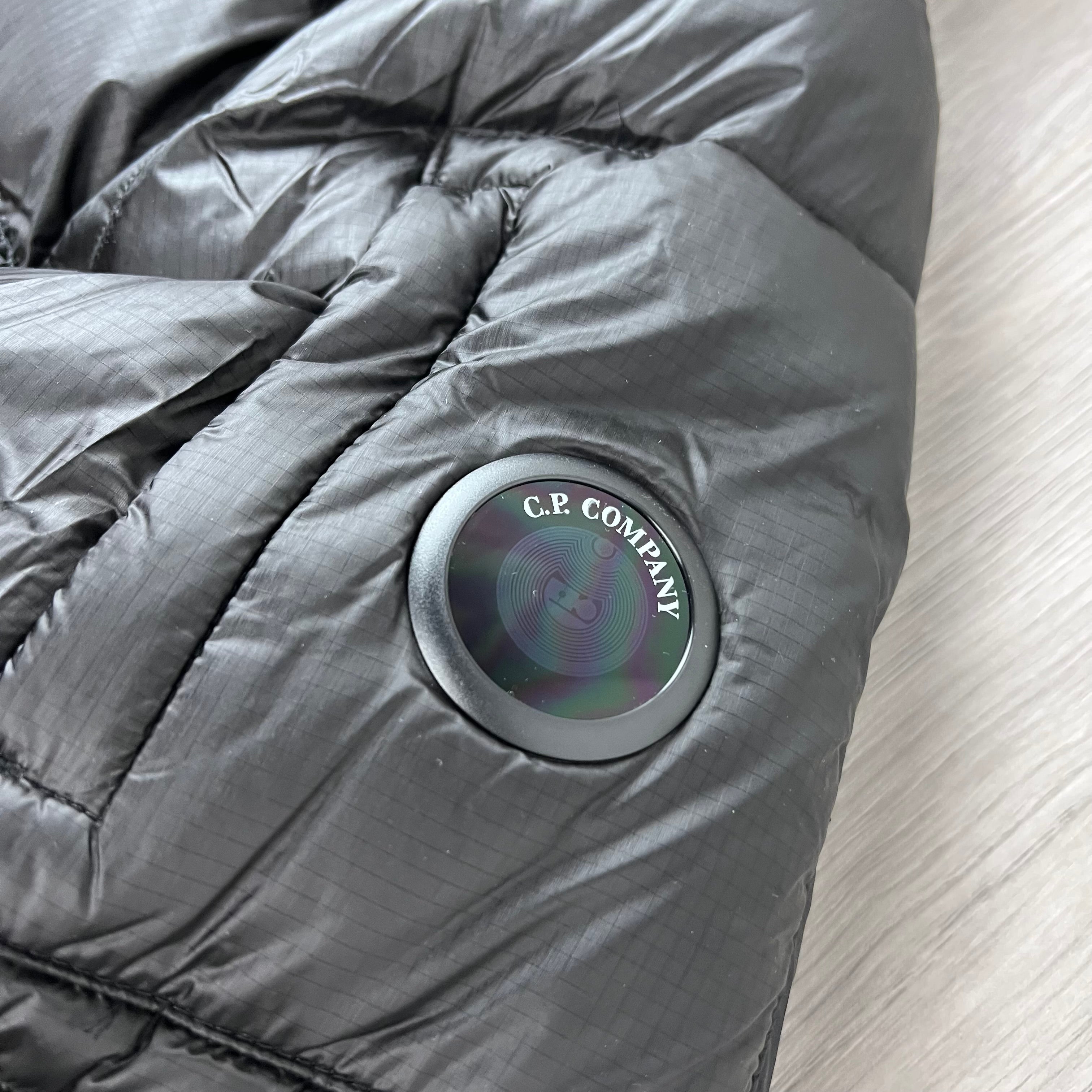A close up view of the sleeve lens on a CP Company D.D. Shell Hooded Down Jacket in Black. 