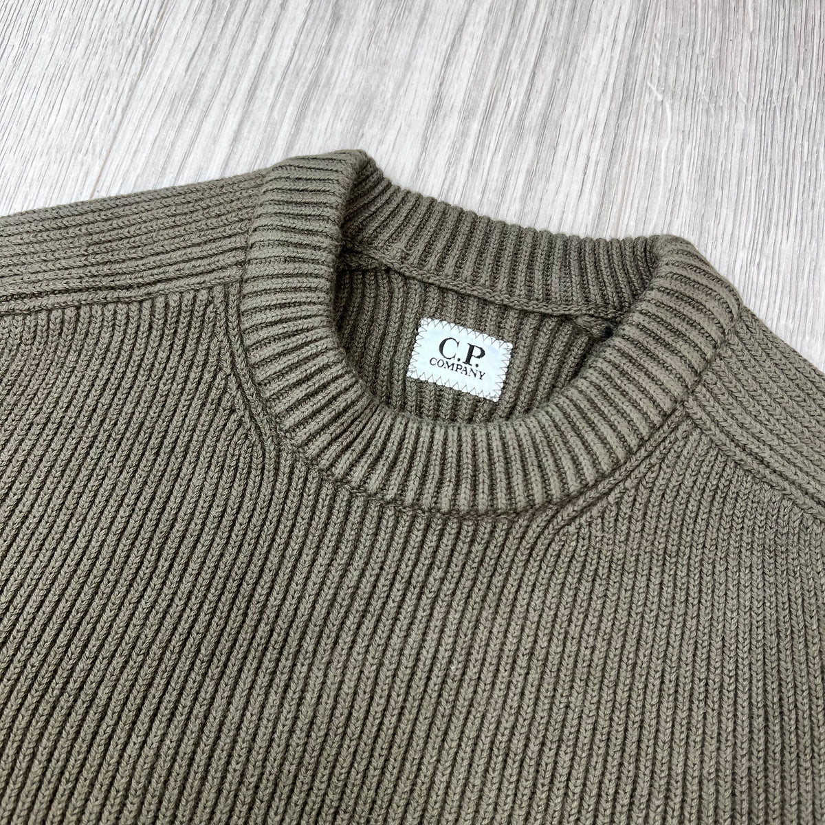 Close up view of the ribbed crewneck collar on a CP Company Full Rib Cotton Knit Sweatshirt in Ivy Green.