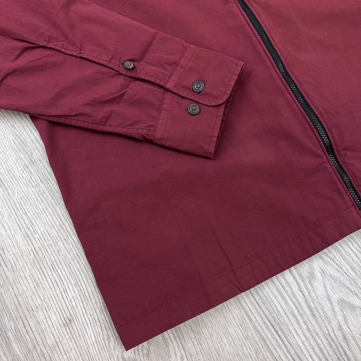 Close up view of the sleeve cuffs and hem on a CP Company Zip Overshirt in Andorra Red. 