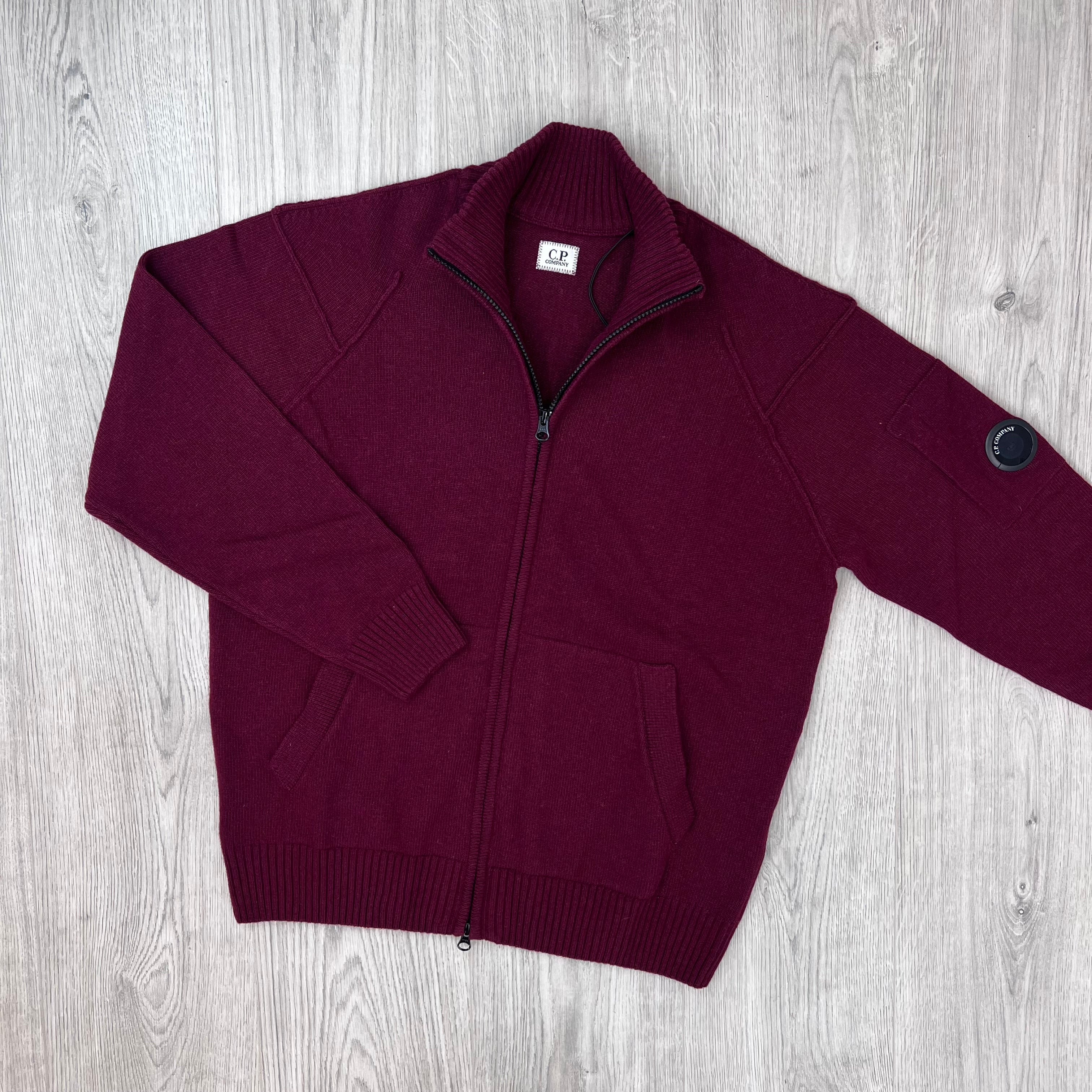 Front image of a CP Company Lambswool Lens Full Zip Sweater in Andorra Red partially unzipped. 