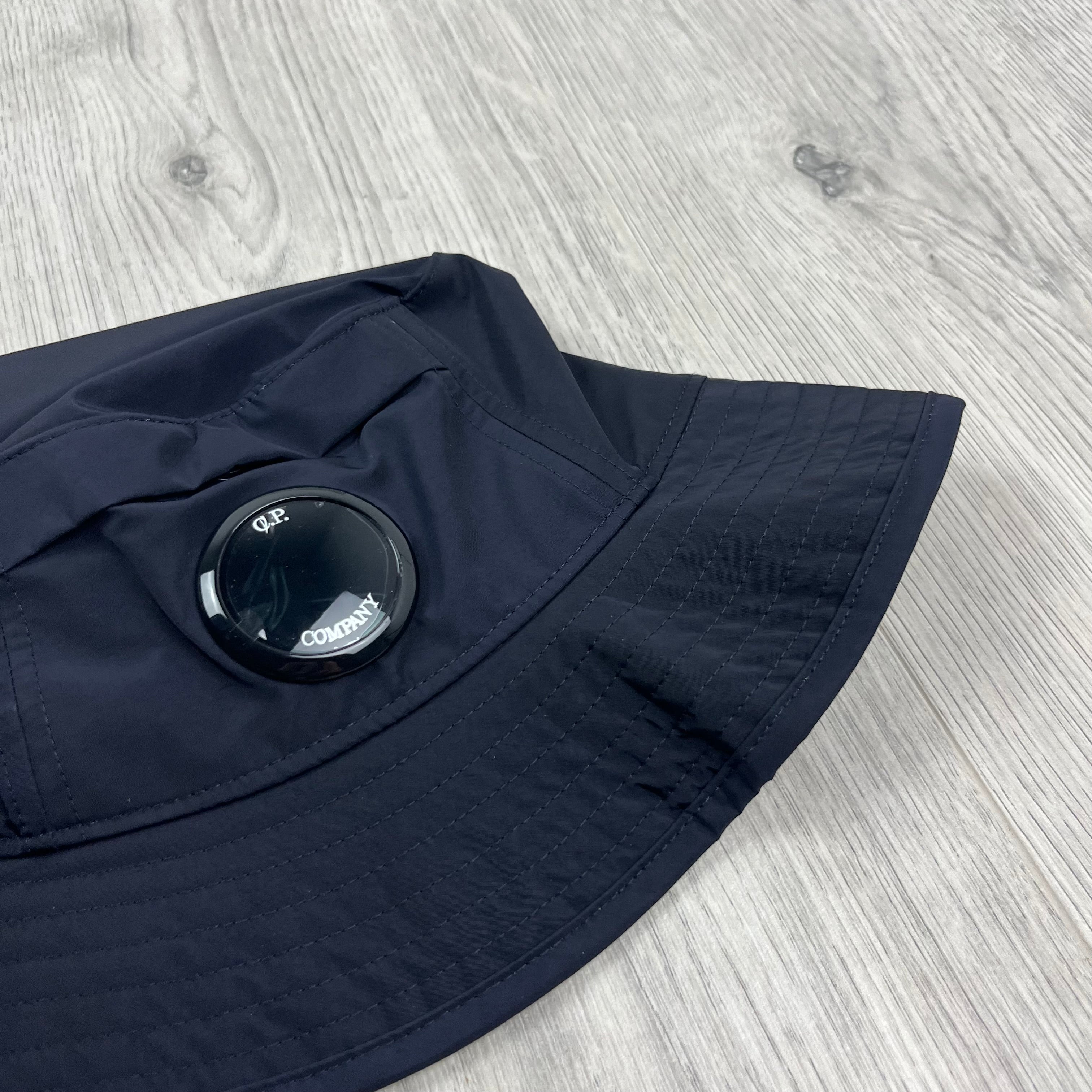 CP Company Lens Bucket Hat in Total Eclipse Navy Blue. On sale at Open Attire.