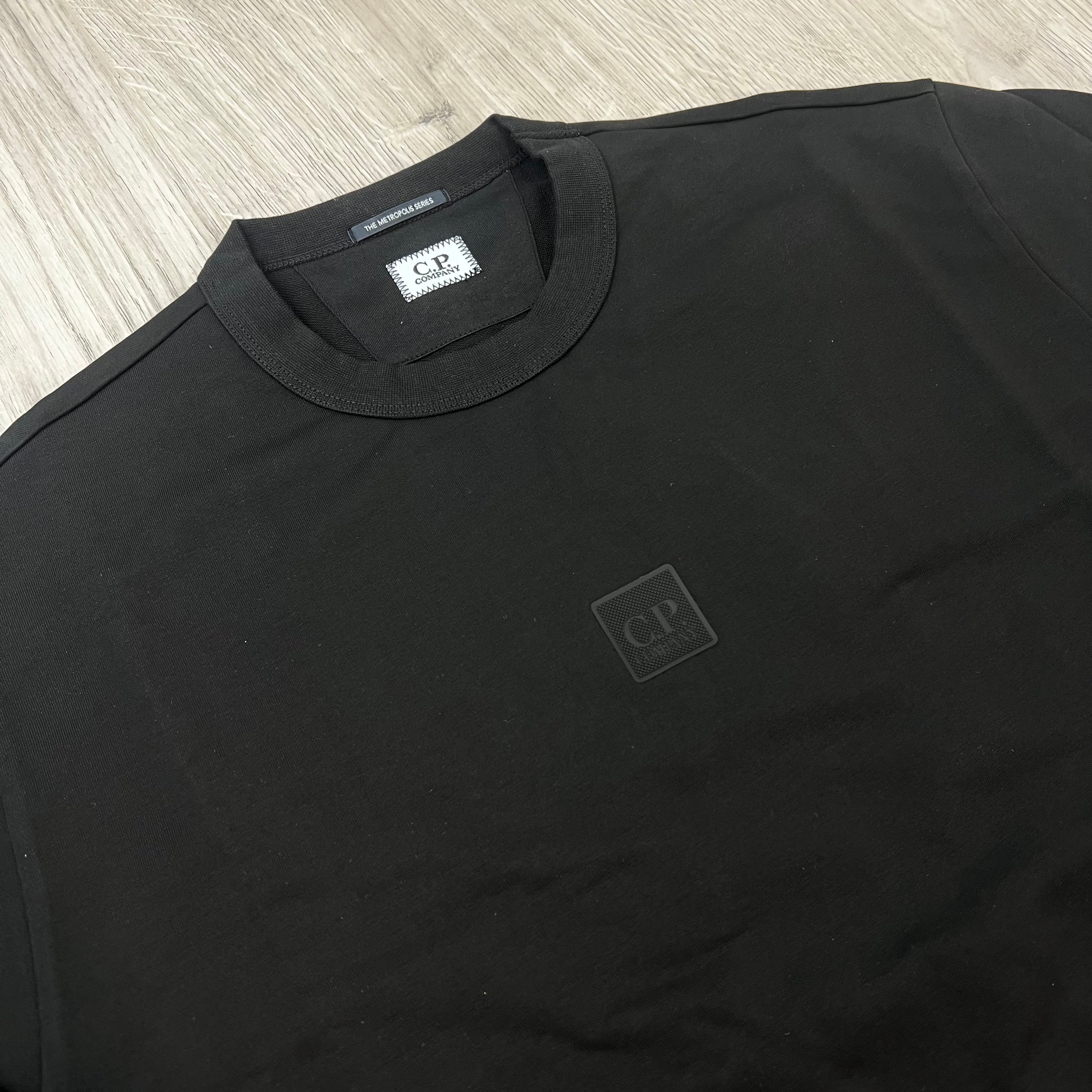 A close up view of a CP Company Metropolis Series Stretch Fleece Sweatshirt with the rubberized patch logo in the centre of the garment. 