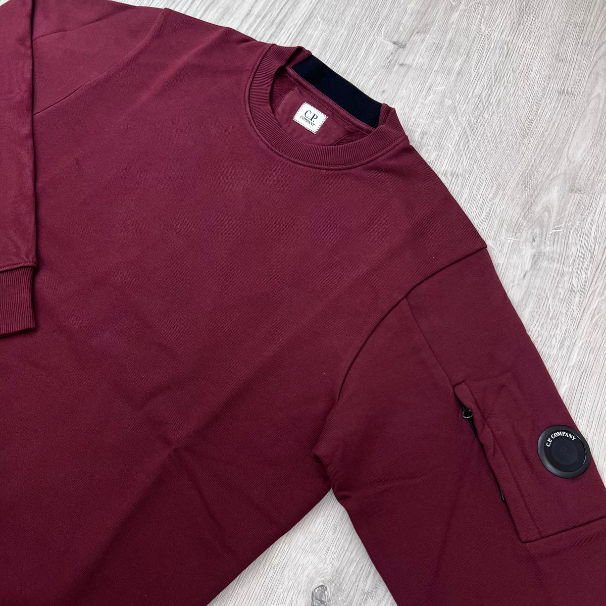 Angled view of the crewneck collar and sleeve lens on a CP Company Raised Fleece Sweatshirt in Andorra. 