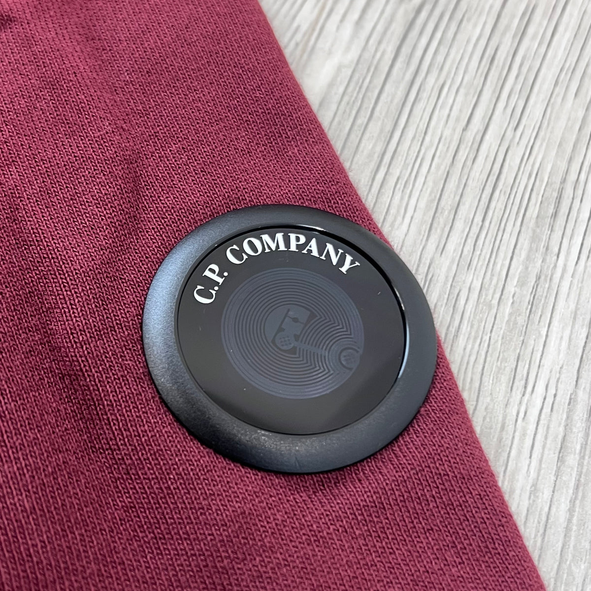 Close up view of the new NFC lens on a CP Company Raised Fleece Sweatshirt in Andorra. 