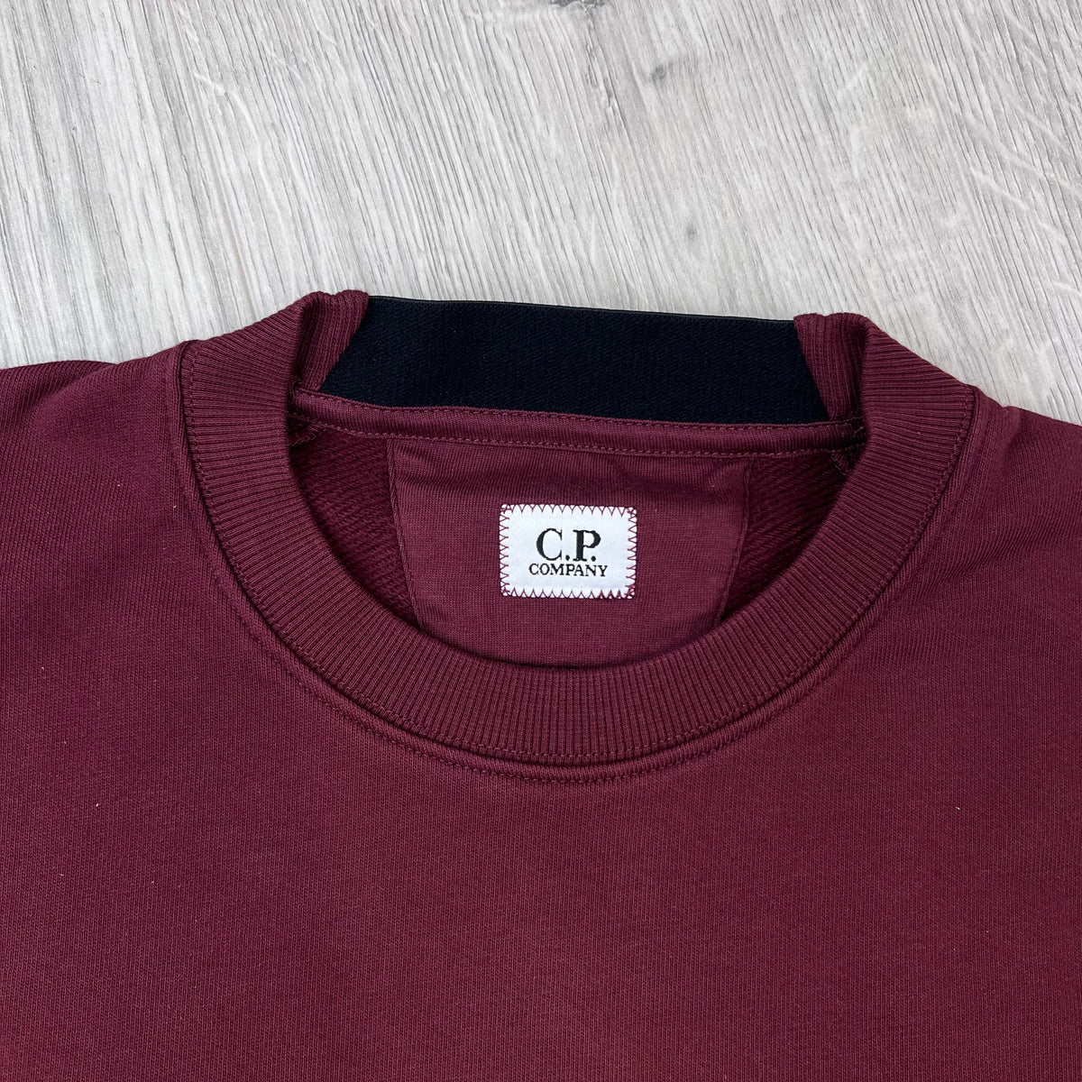 Close up view of the ribbed crewneck collar on a CP Company Raised Fleece Sweatshirt in Andorra. 