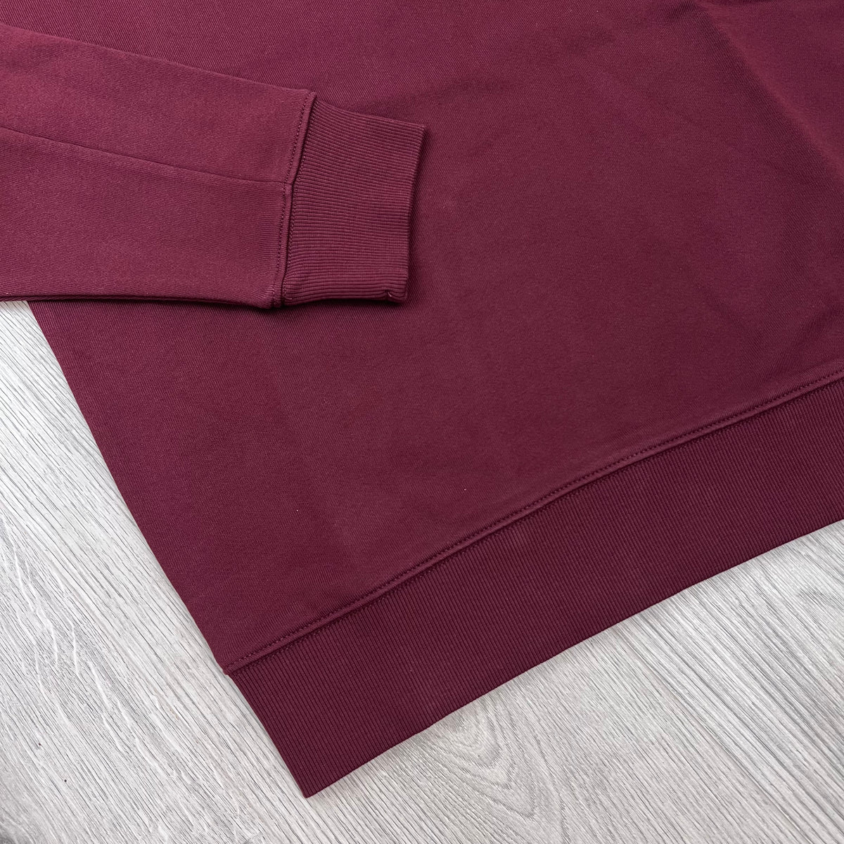 Close up view of the ribbed hem and cuffs on a CP Company Raised Fleece Sweatshirt in Andorra. 