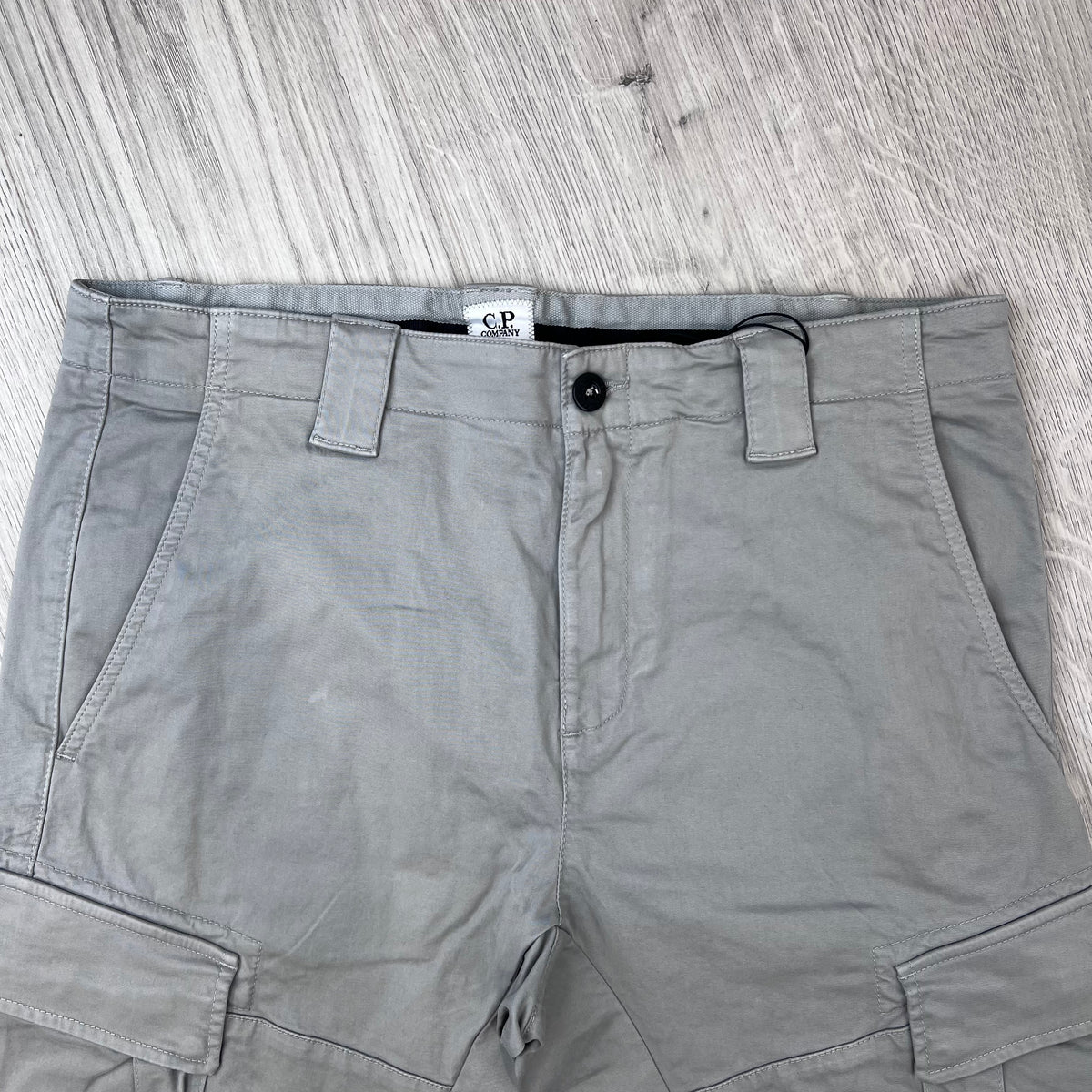 Close up of the view of the waist closure on the CP Company Stretch Sateen Cargo Trousers in Flint Grey. 